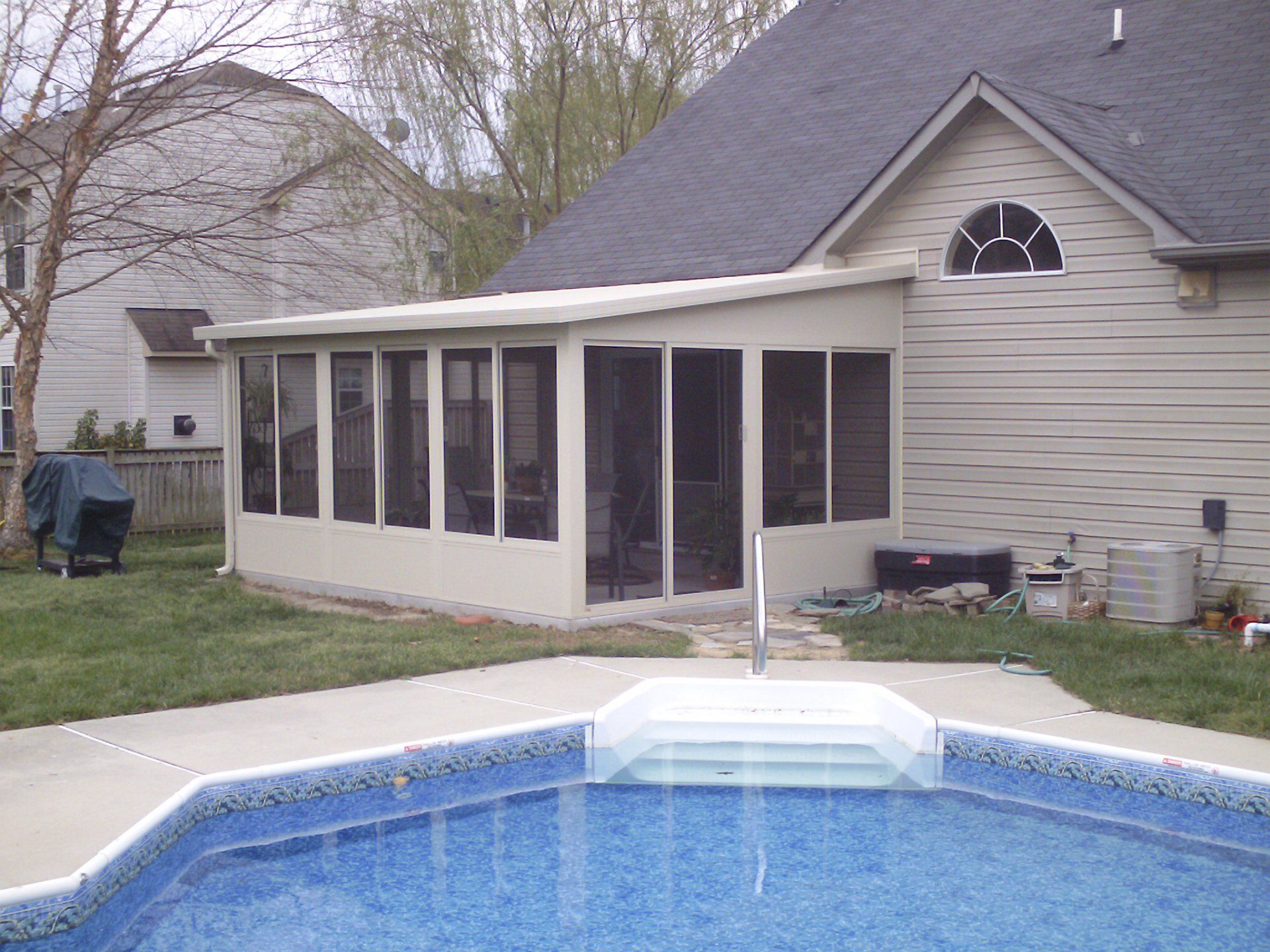 A house with a screened in porch next to a swimming pool