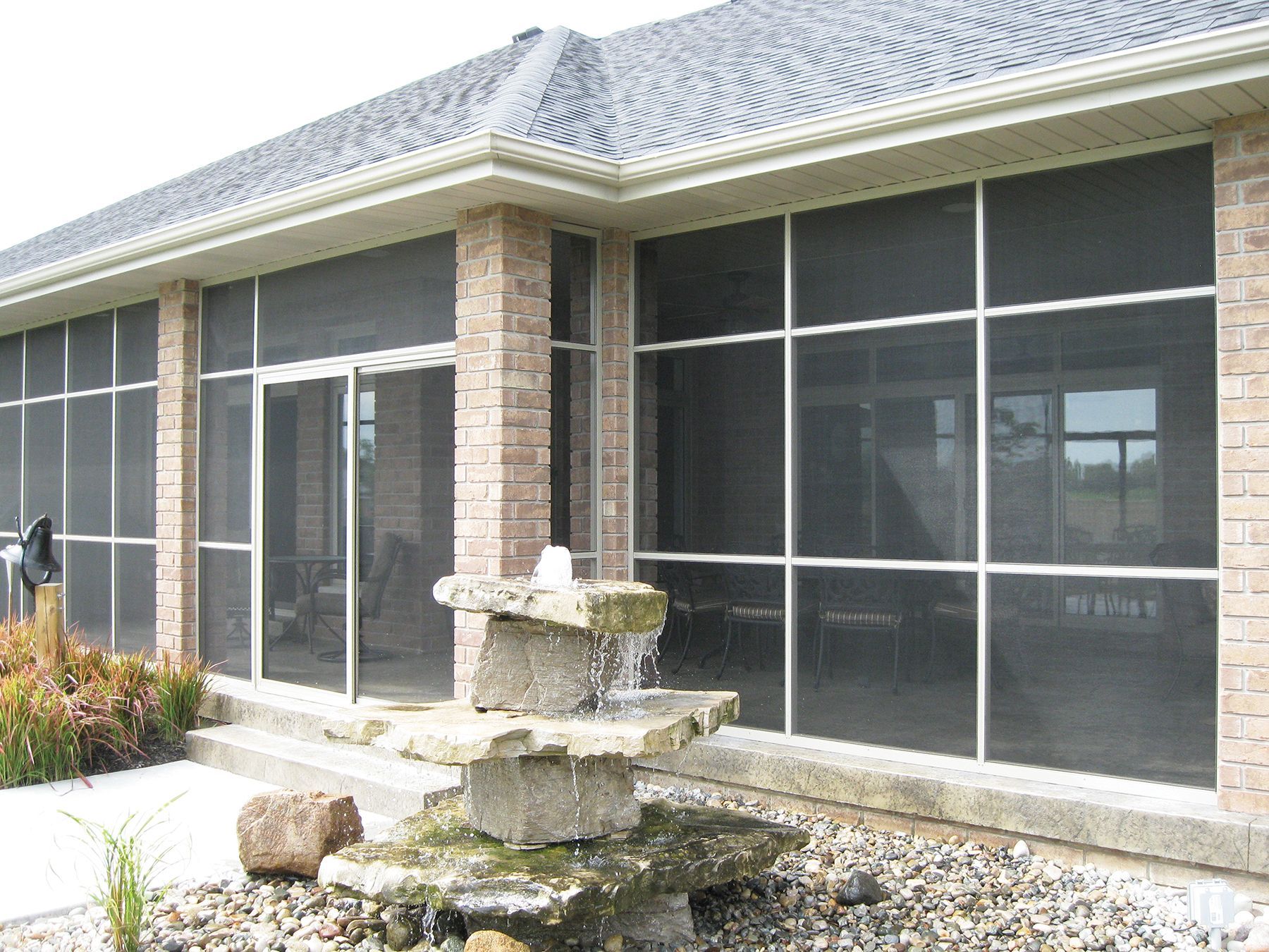 A screened in porch with a fountain in front of it