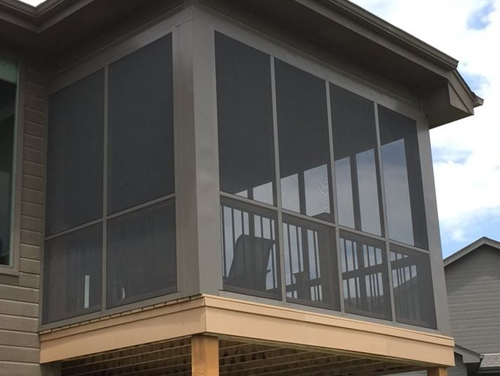 A screened in porch on the side of a house.