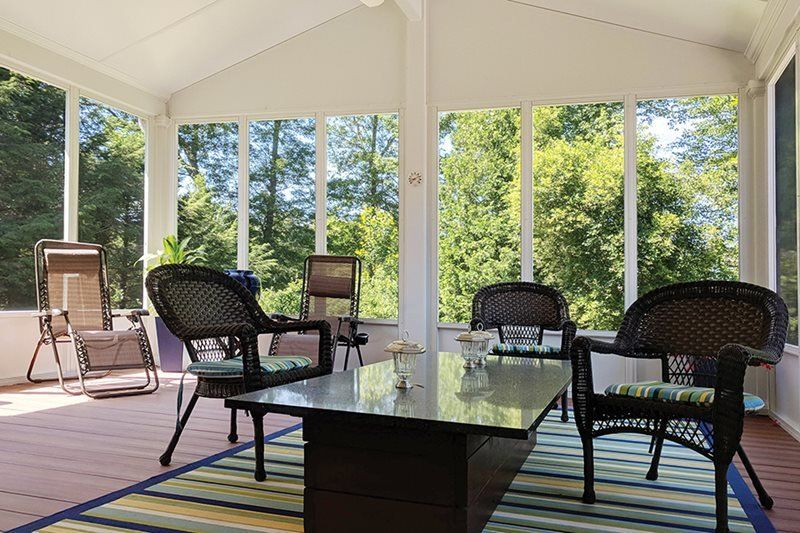 A screened in porch with wicker chairs and a table