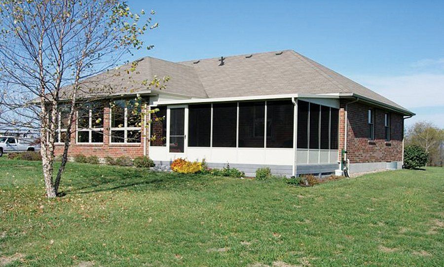 a brick house with a screened in porch in the backyard .