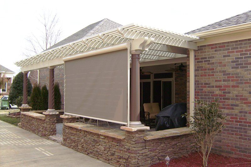 A brick house with a pergola and a screen on the porch