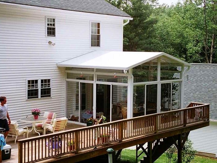 A white house with a sunroom and a wooden deck