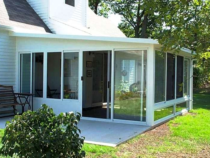 A white house with a screened in porch with sliding glass doors
