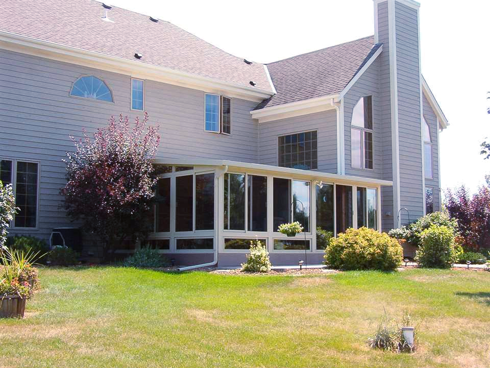 A large house with a screened in porch and lots of windows