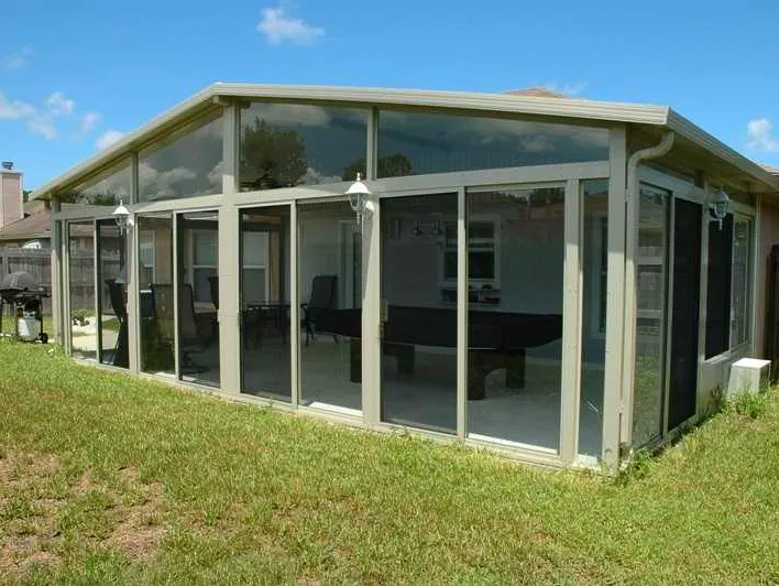 A screened in porch with a pool table in the backyard of a house.