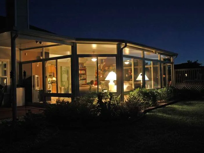 A house with a lot of windows is lit up at night