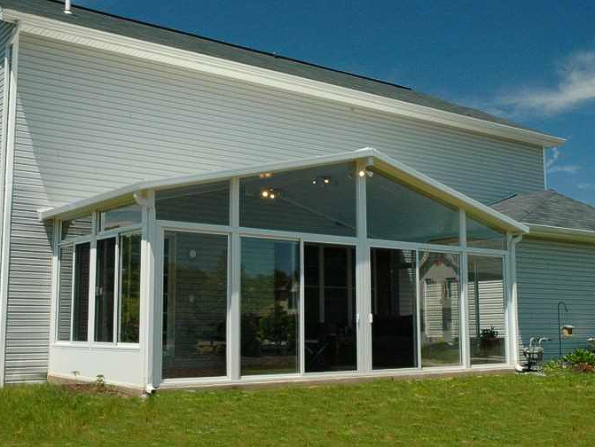 A white house with a screened in porch with a lot of windows.