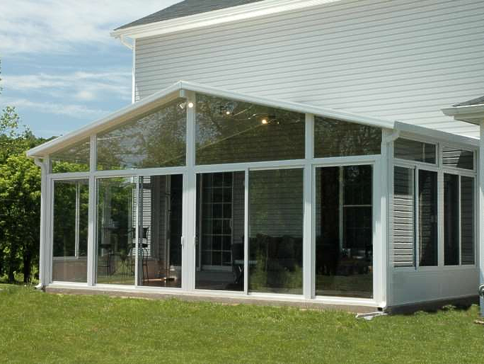 A white house with a screened in porch with lots of windows