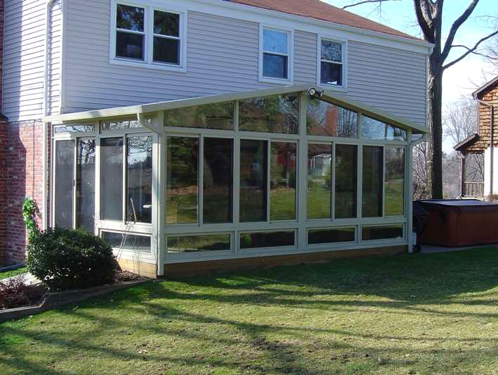 A house with a sunroom and a hot tub in the backyard