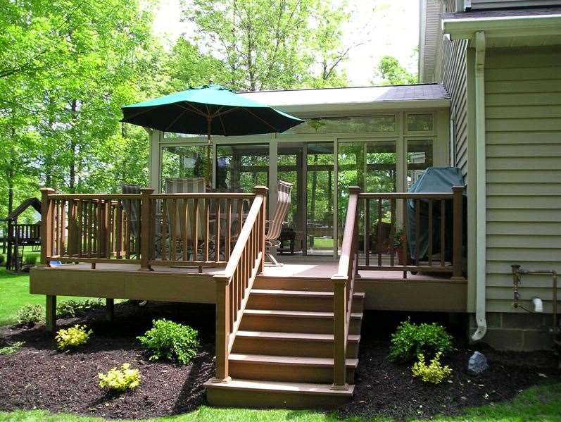 A deck with stairs leading up to it and a green umbrella