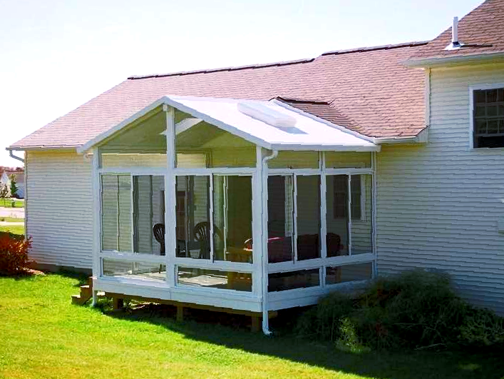 A white house with a screened in porch in front of it