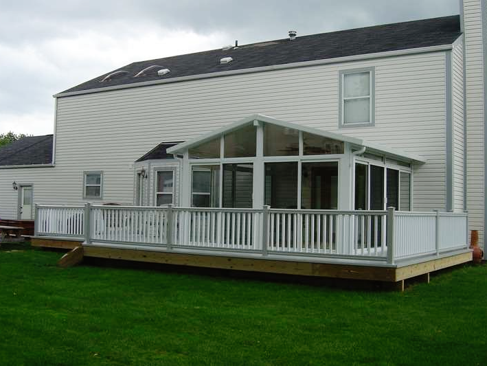 A white house with a screened in porch in front of it