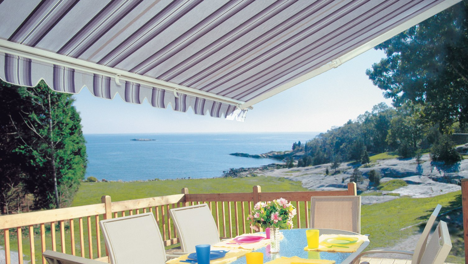 A table and chairs under an awning overlooking the ocean