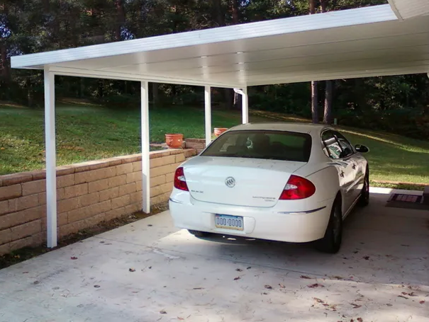 A white car is parked under a white carport
