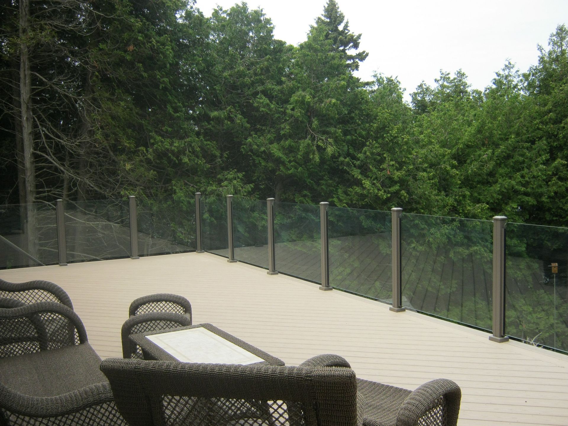 A deck with wicker furniture and a glass railing