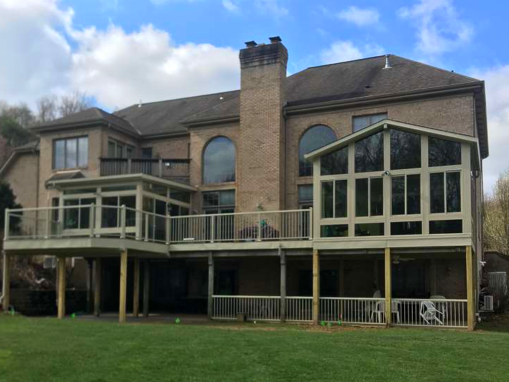 The back of a large brick house with a large deck.