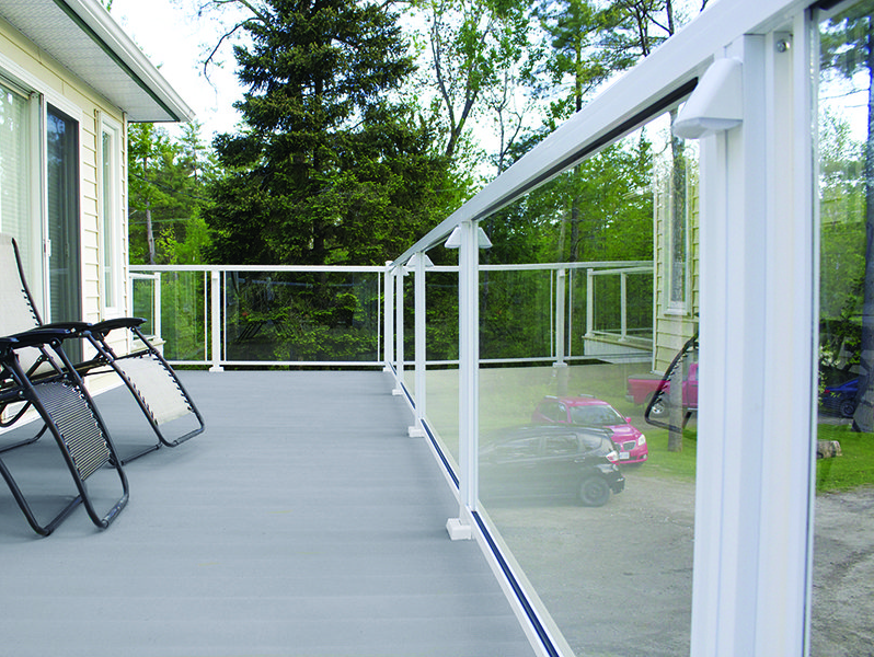 A deck with a white railing and clear glass