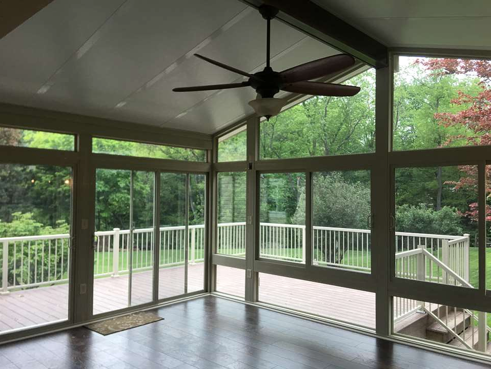 An empty room with a ceiling fan and lots of windows