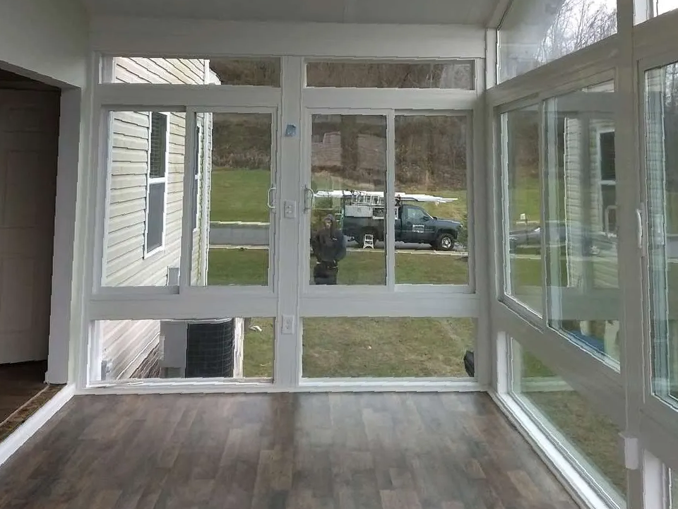 A room with a lot of windows and a car parked in the backyard.