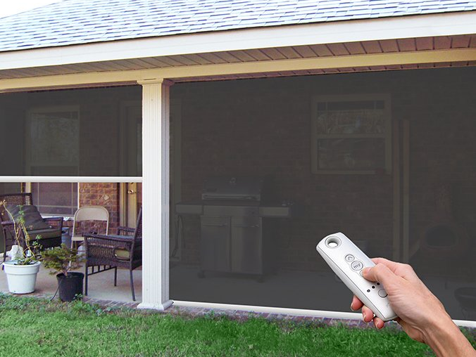 A person is holding a remote control in front of a screened in porch