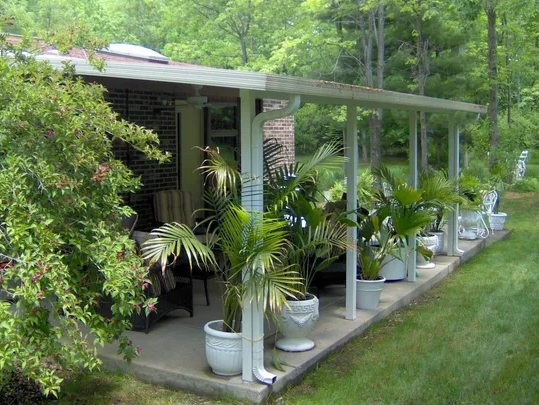 A covered porch with lots of potted plants on it