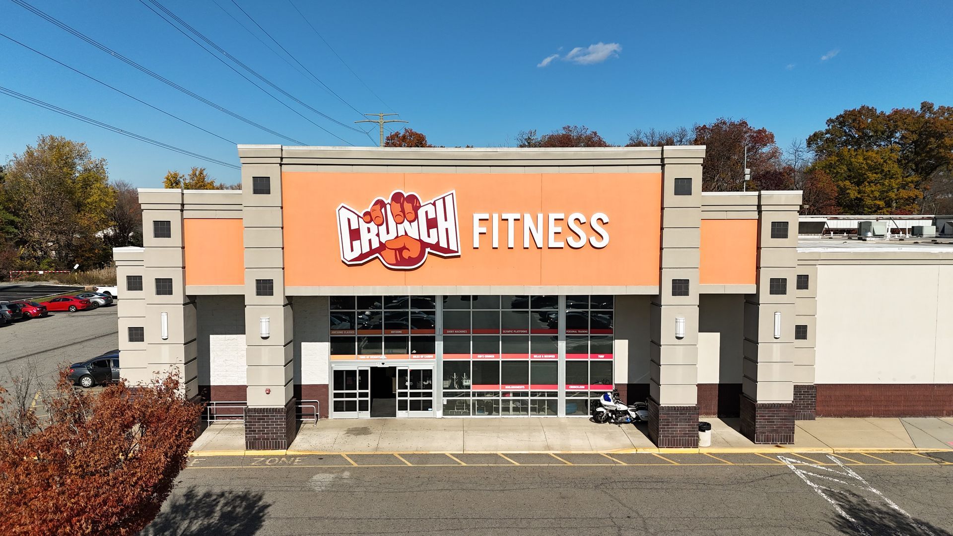 Crunch Fitness building with orange and gray facade, under a clear blue sky.
