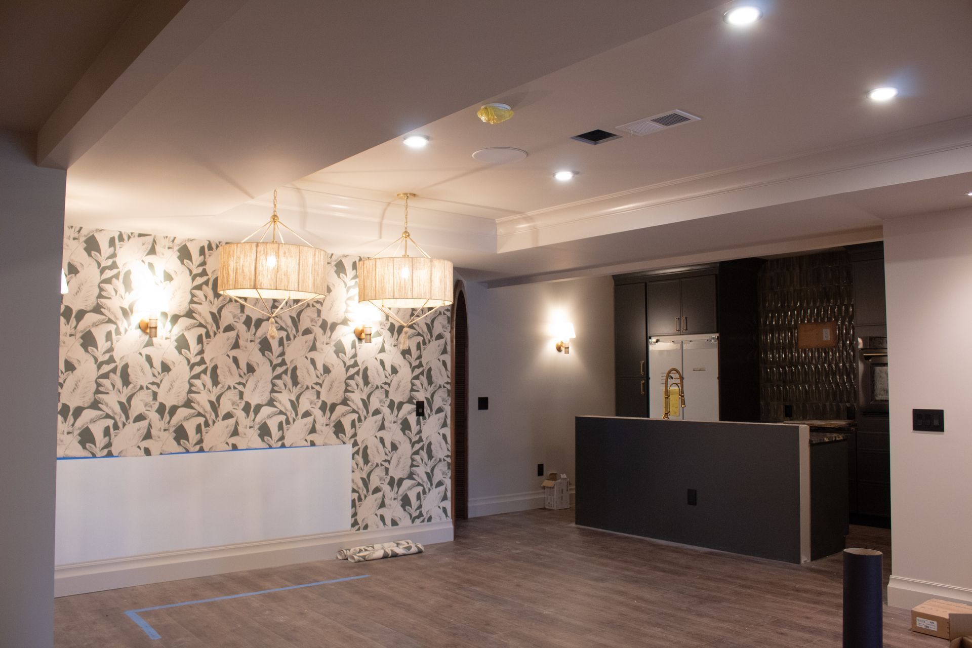 Newly renovated interior with patterned wallpaper, pendant lights, and a kitchen area.