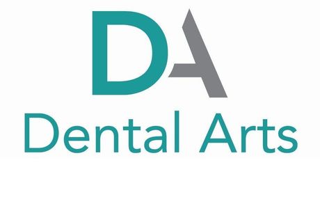 A white brick building with a black roof and a sign that says da dental arts.