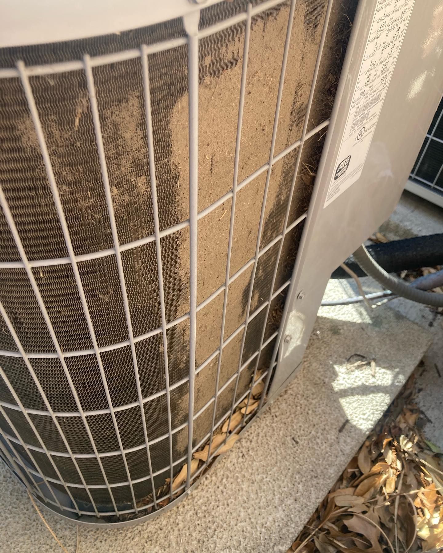 A close up of a dirty air conditioner on a sidewalk.
