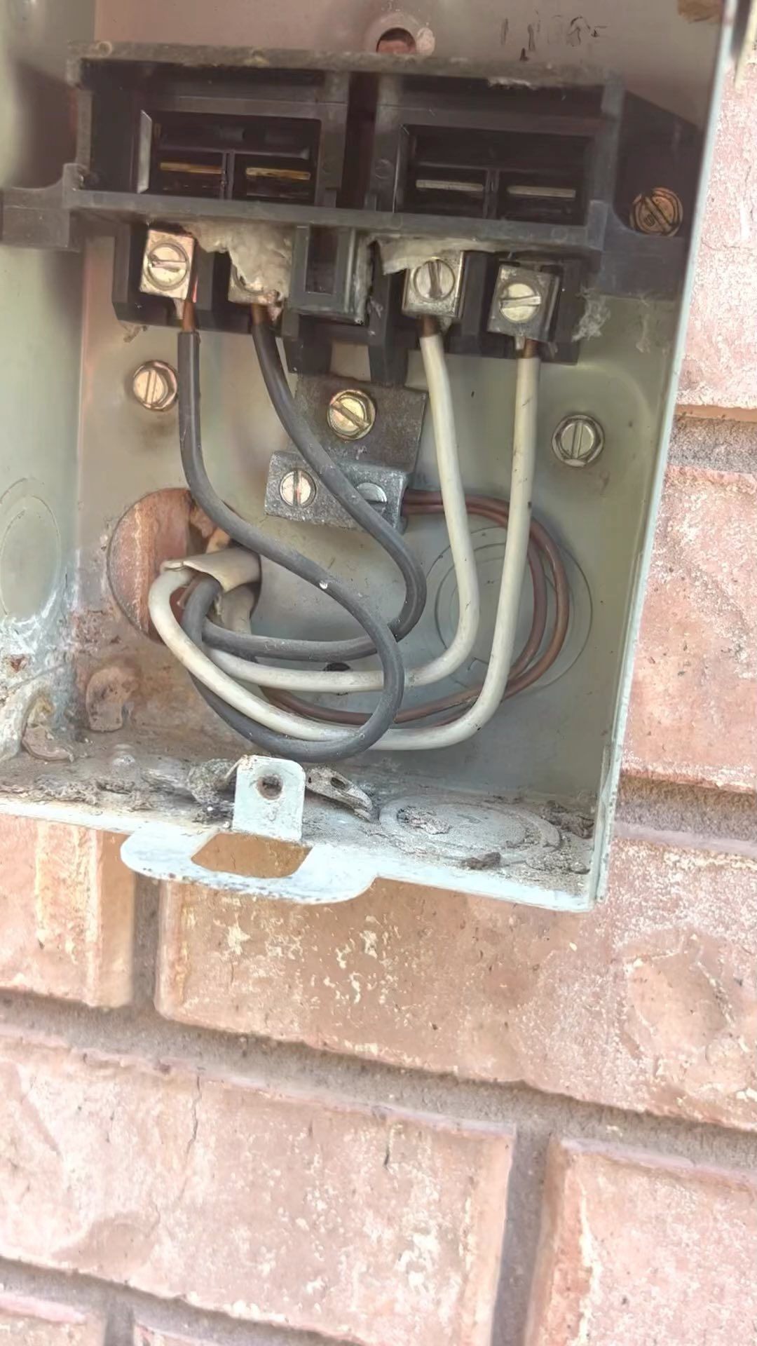 A close up of an electrical box on a brick wall.