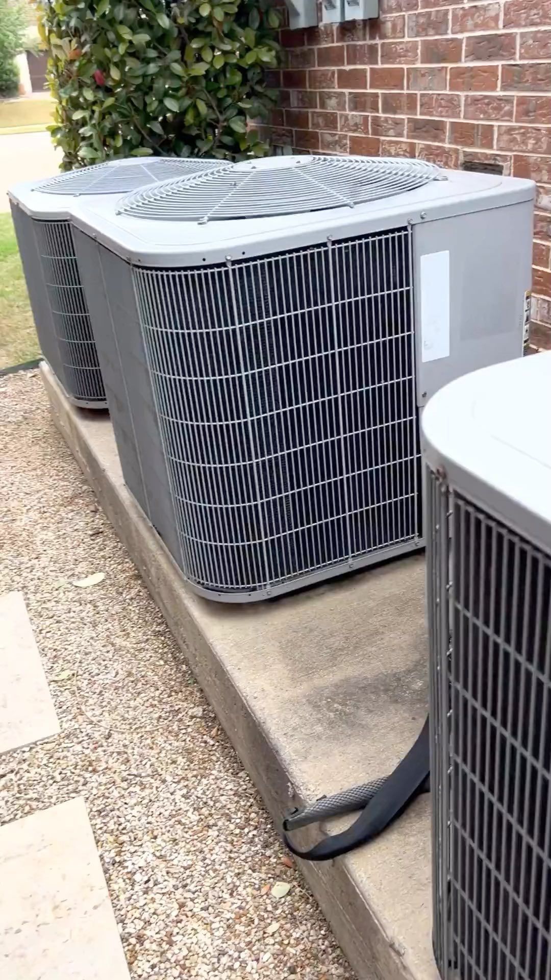Three air conditioners are sitting on the side of a brick building.