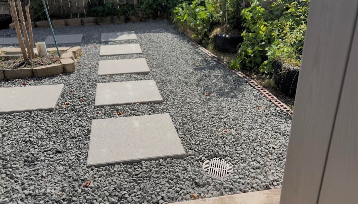 A gravel path with concrete stepping stones in a garden.