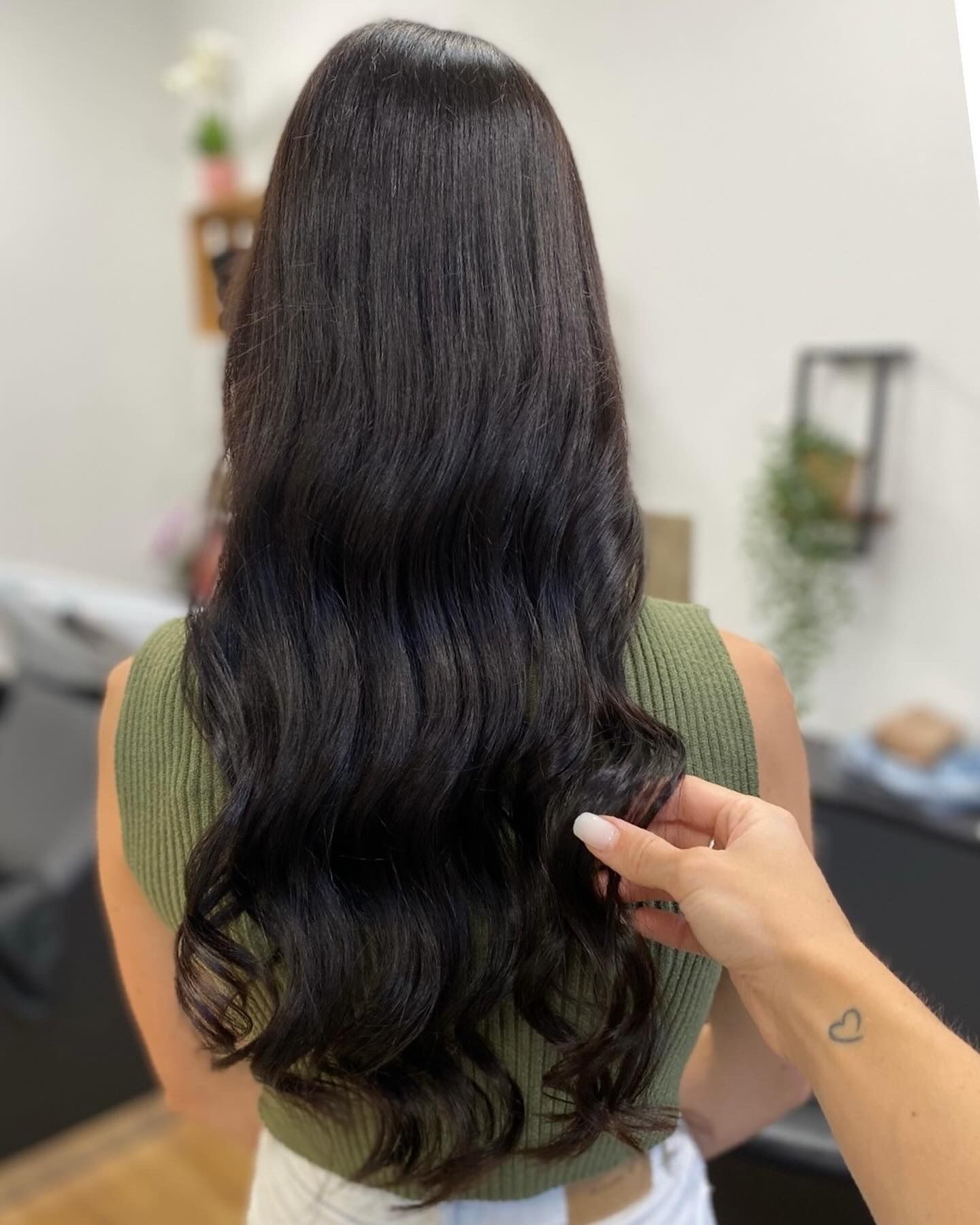 Eine Frau mit langem schwarzen Haar lässt sich in einem Salon die Haare machen.