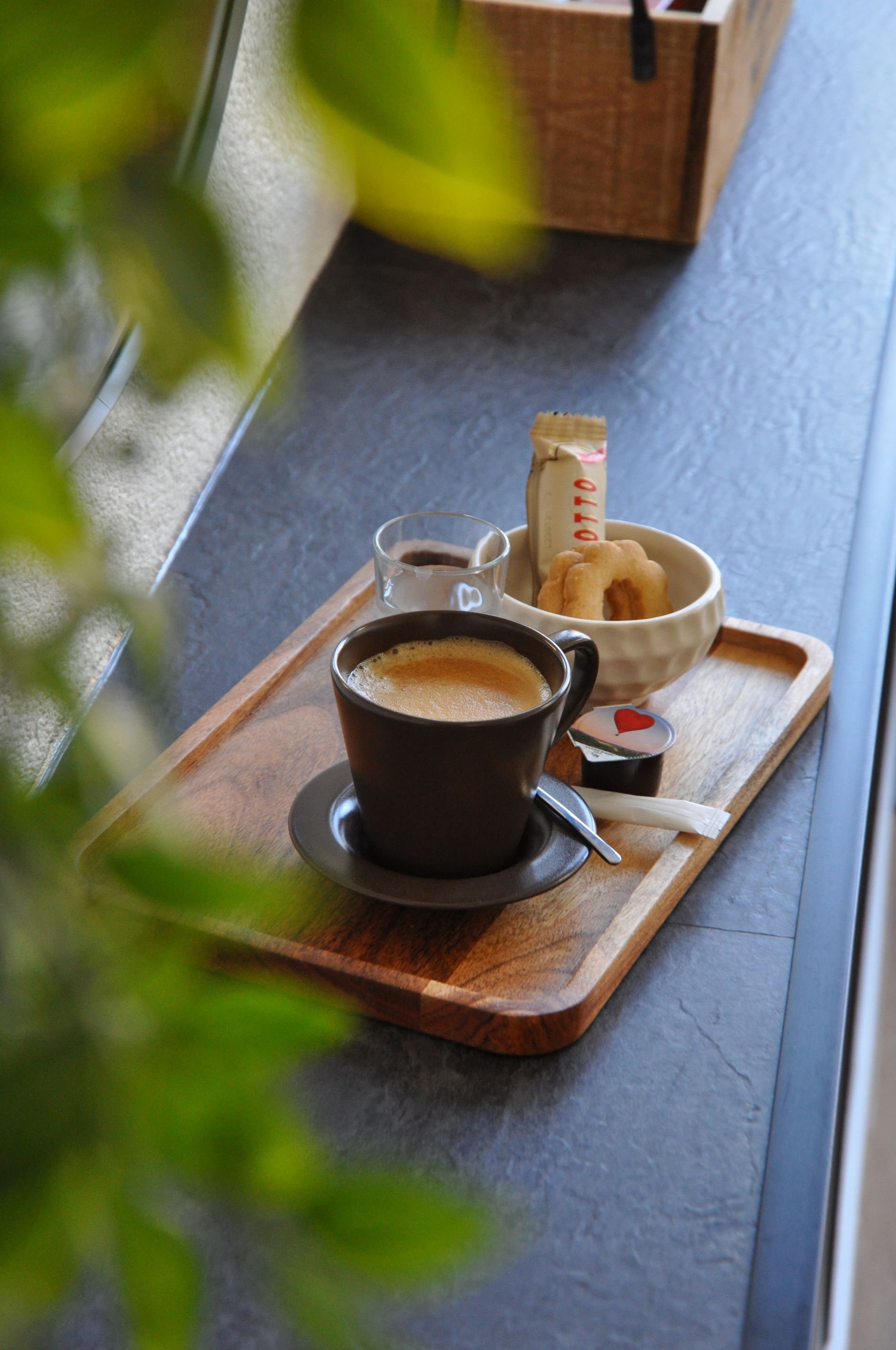 Eine Tasse Kaffee und eine Schüssel Kekse auf einem Holztablett.