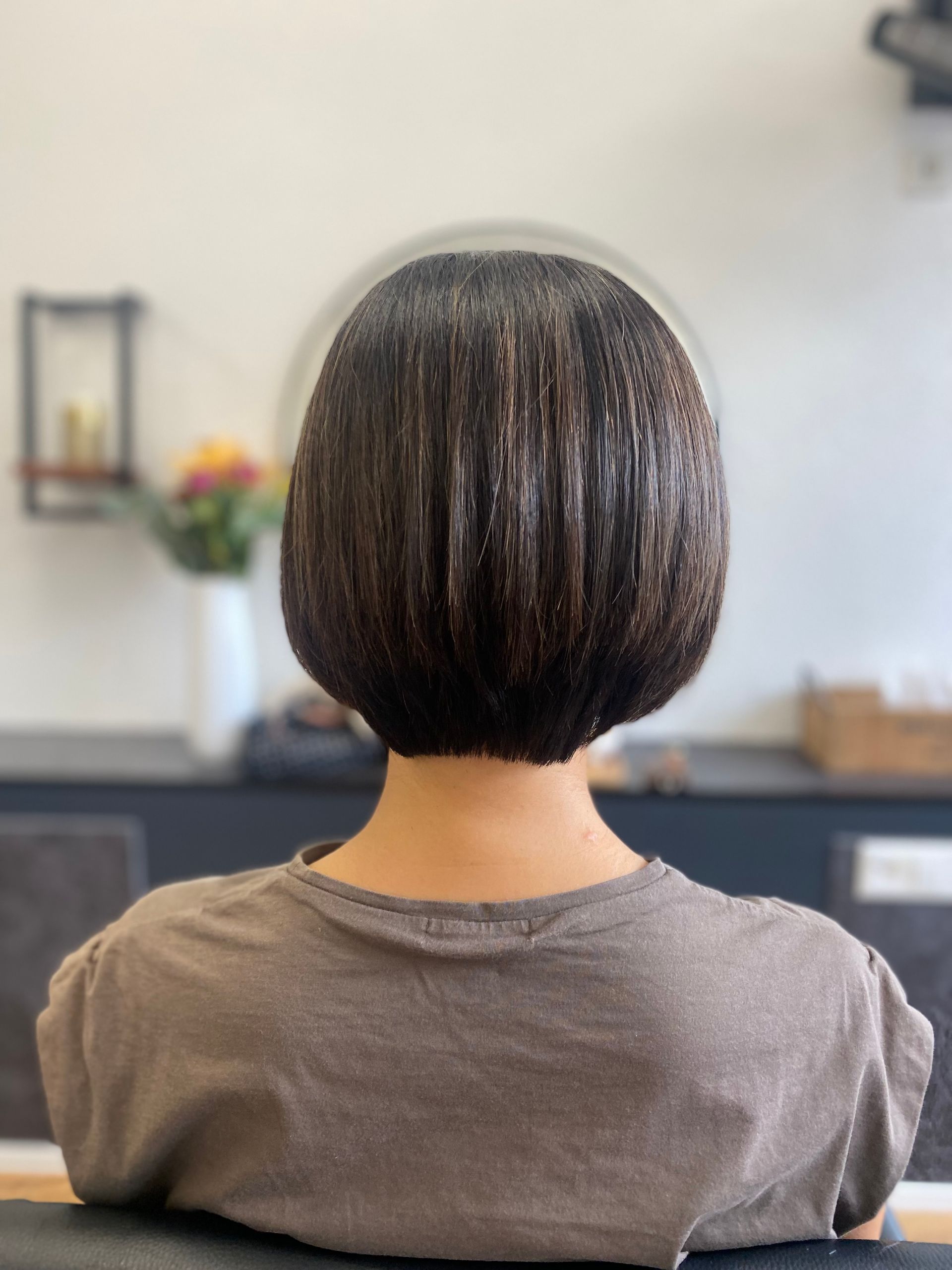 Eine Frau mit kurzen Haaren sitzt mit dem Rücken zur Kamera auf einem Stuhl.