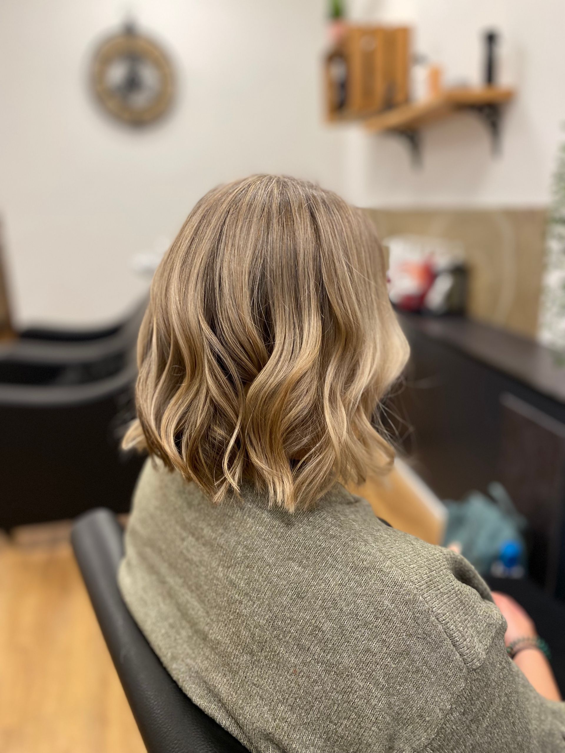 Eine Frau sitzt in einem Friseursalon auf einem Stuhl und frisiert.