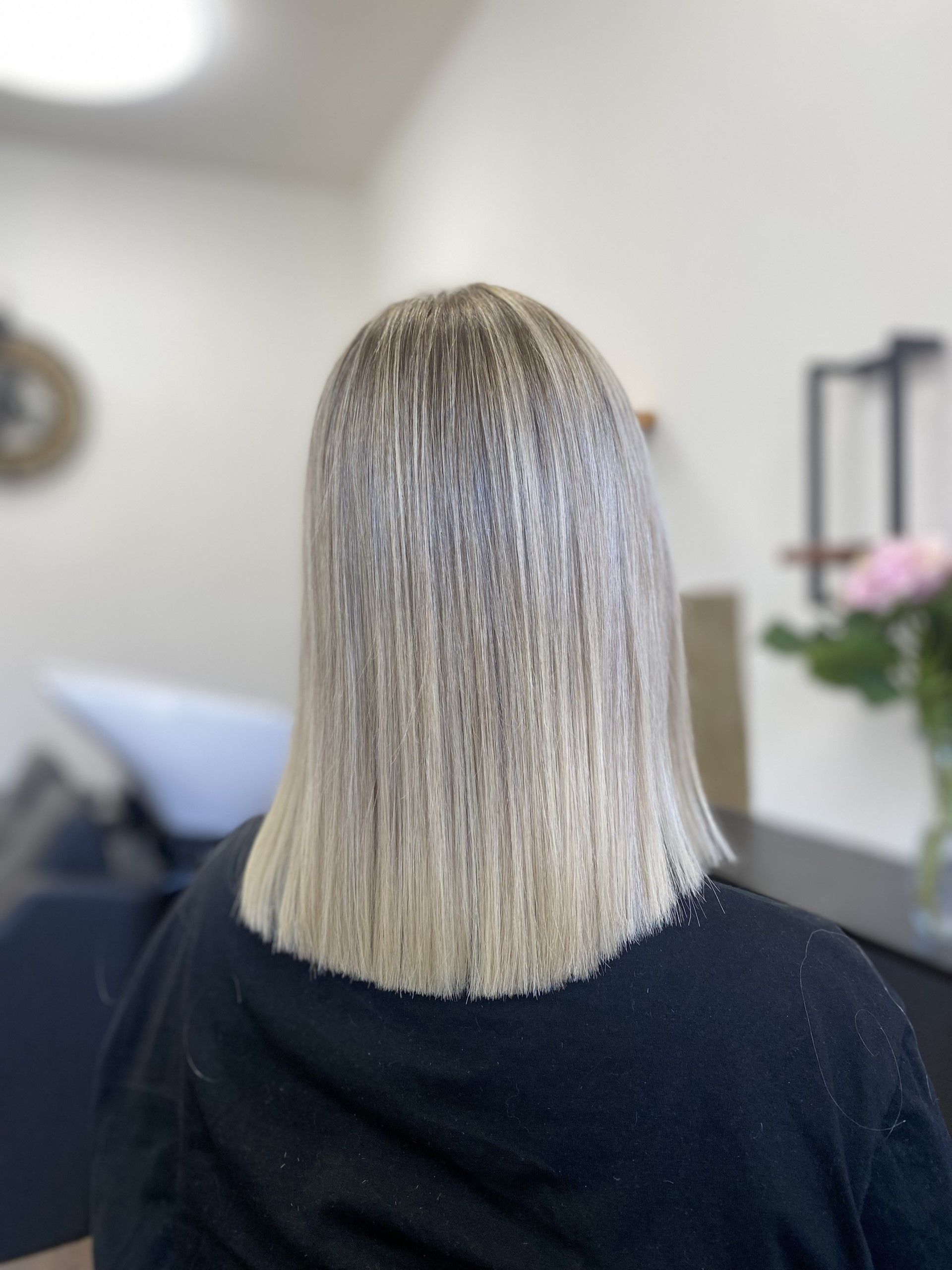 Eine Frau mit blonden Haaren sitzt in einem Salon auf einem Stuhl.