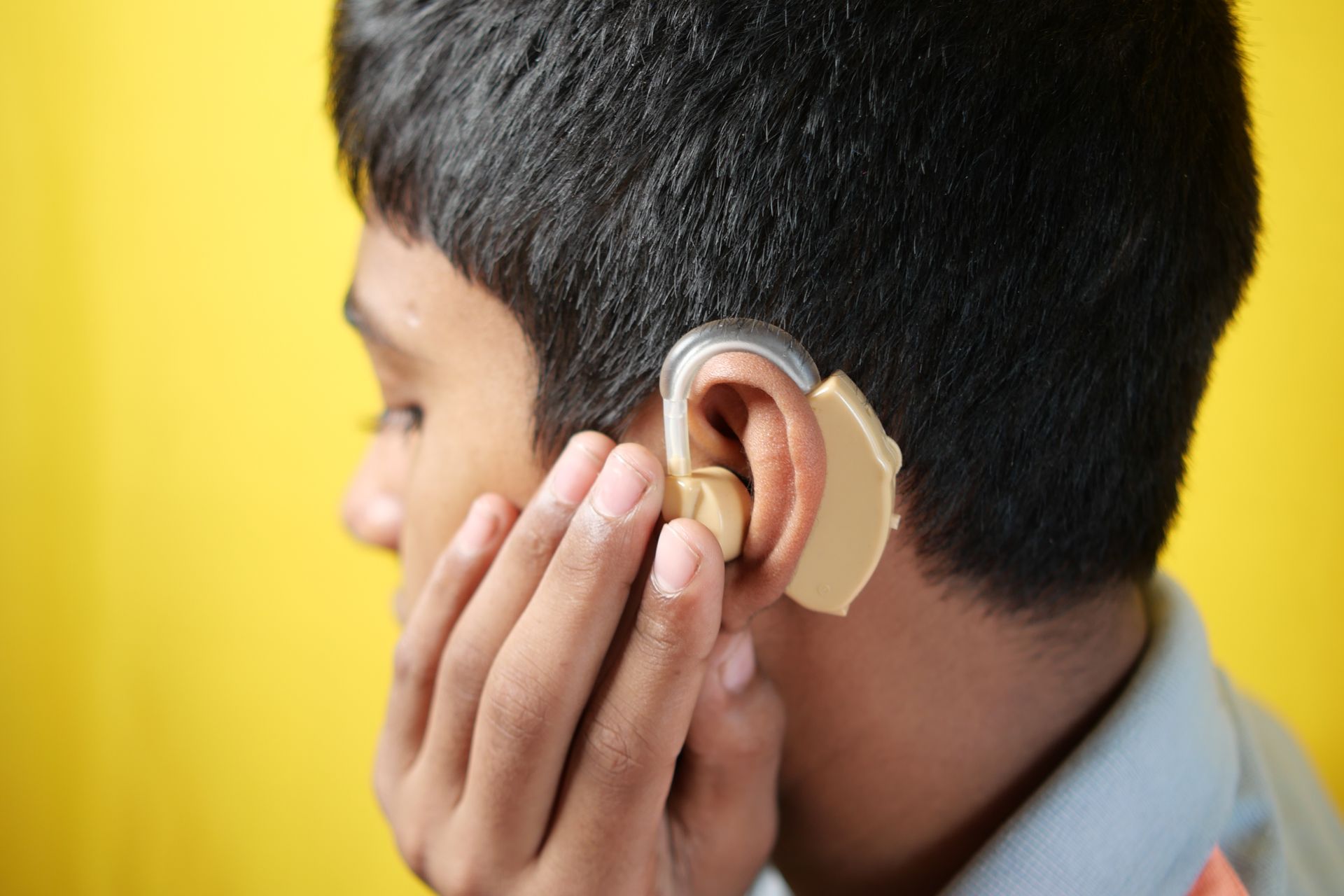 A teenage boy with hearing problems is using a hearing aid.