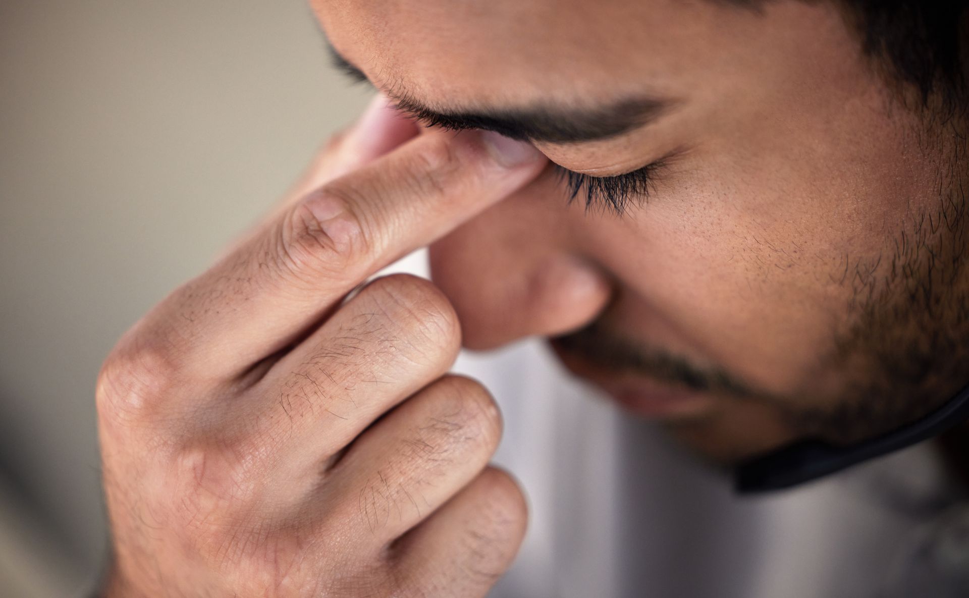 A man is holding his nose because he has a headache due to chronic rhinitis.