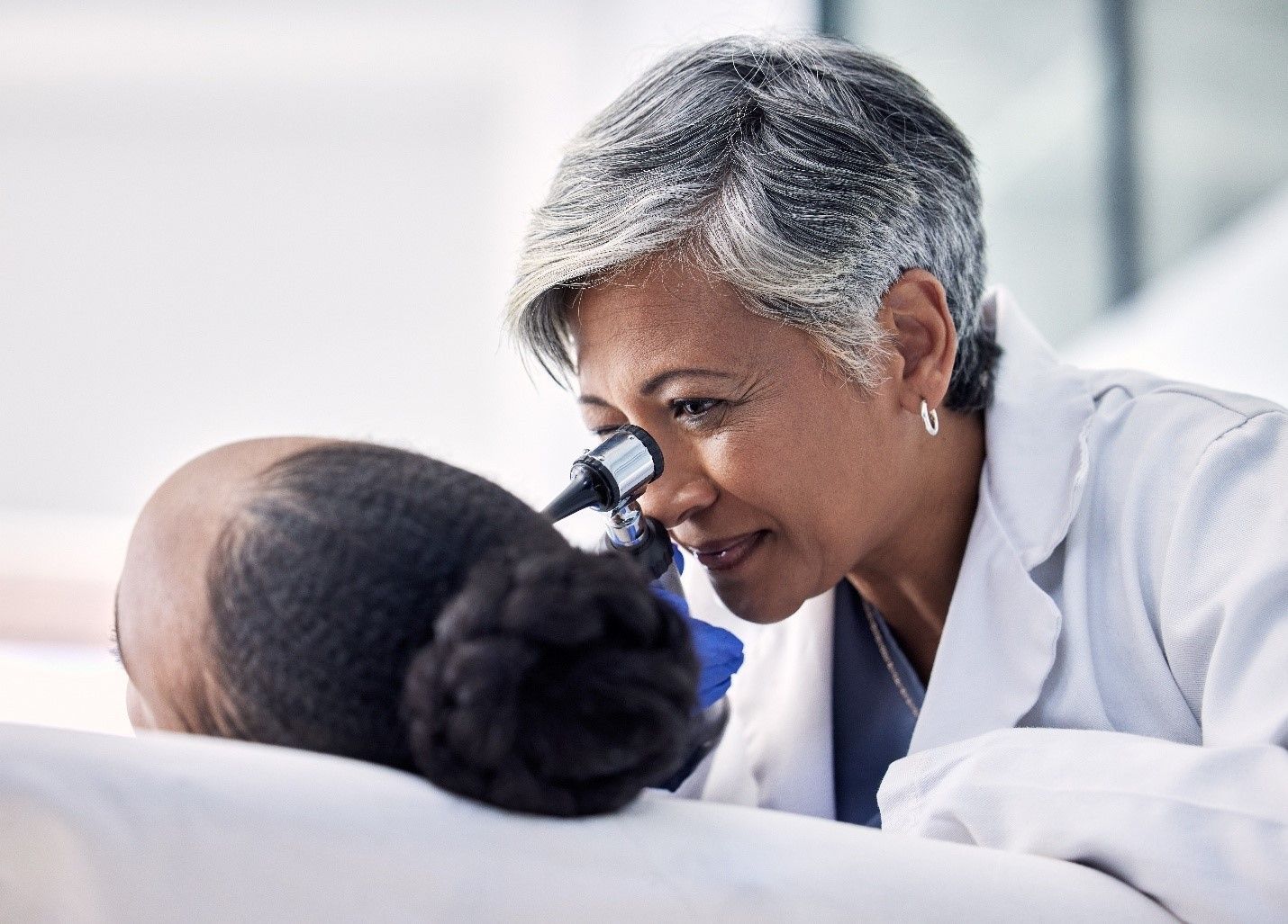 A Audiologist is examining a patient 's ear.