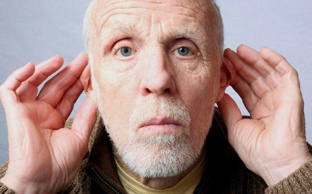 A man with a hearing problem is covering his ears with his hands.