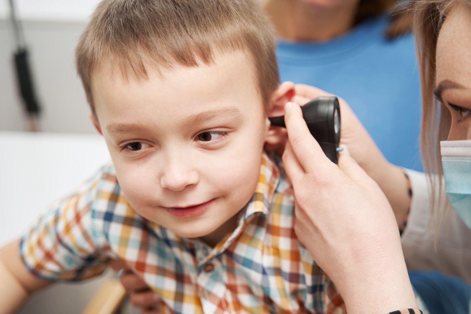 A doctor is examining a young boy 's ear with a stethoscope.
