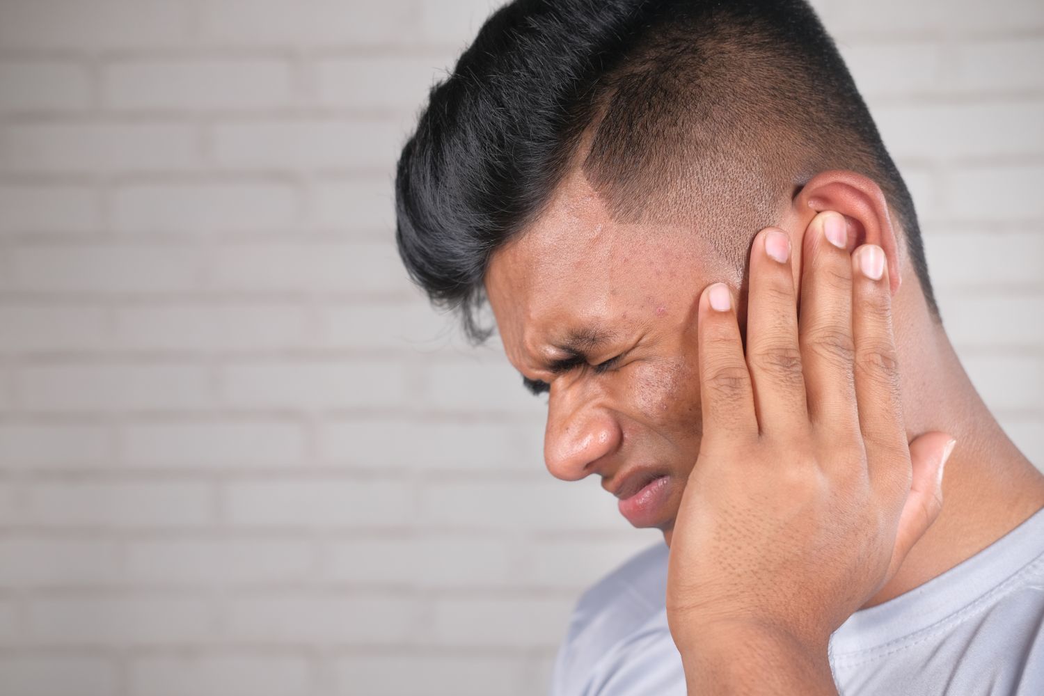 A man holding his ear due to ear ache.