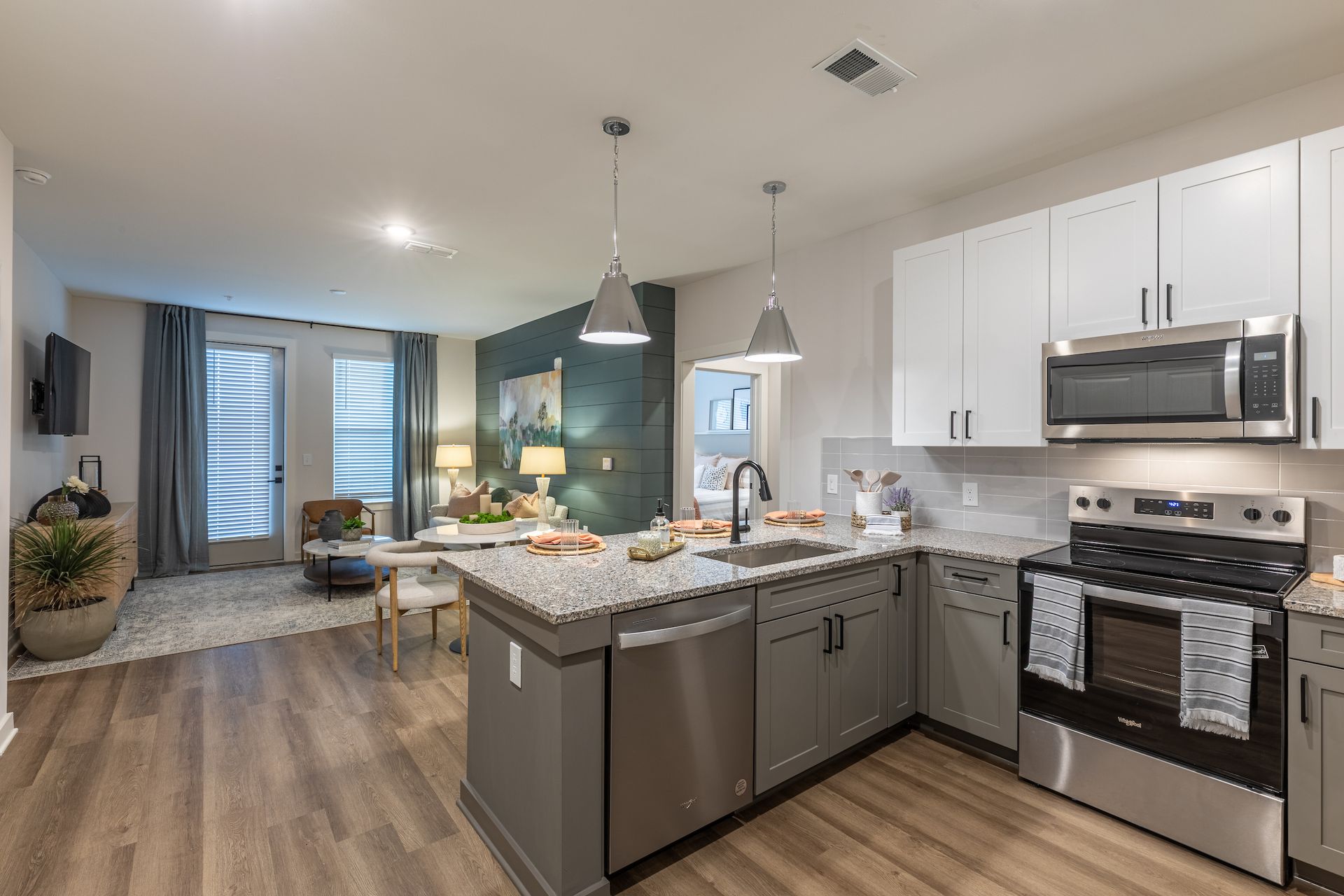 Modern kitchen with gray and white cabinets, stainless steel appliances, and a granite countertop island.