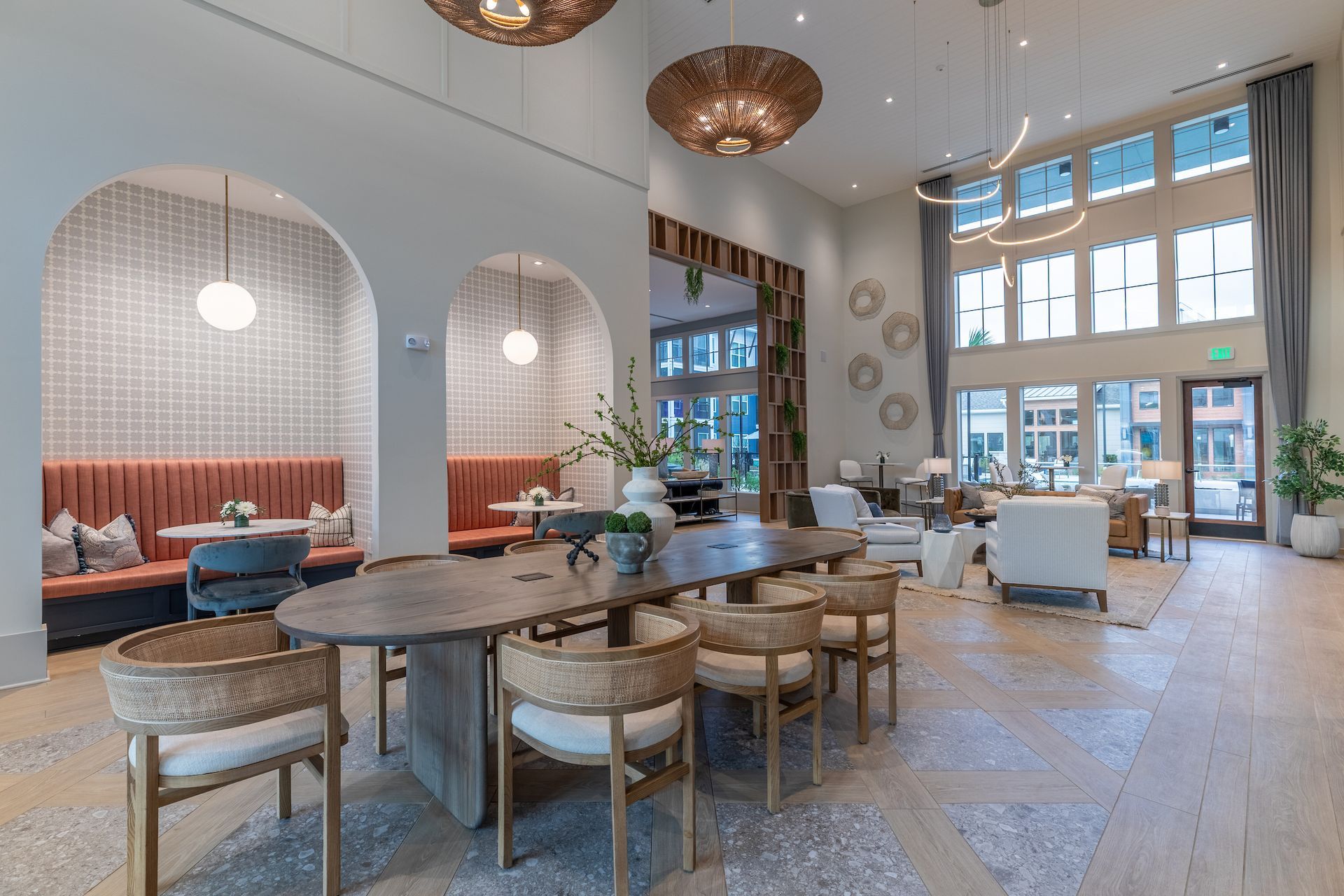 Spacious lobby with wood floors, seating areas, large windows, and decorative lighting.