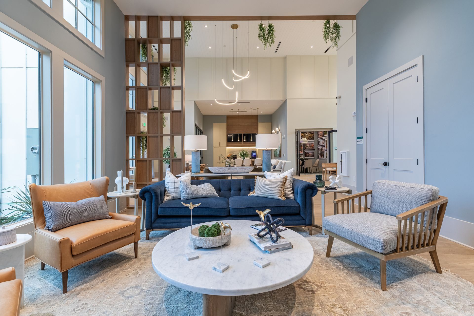 Living room with blue sofa, two armchairs, a large mirror, and open shelving.