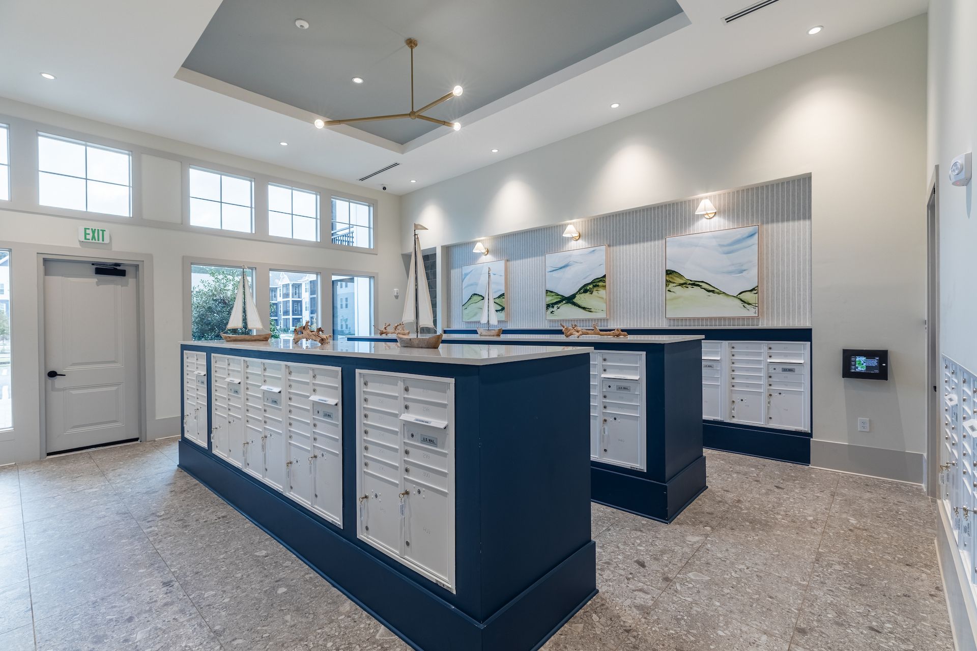 Apartment mailboxes in a brightly lit room with artwork. White and navy blue accents.