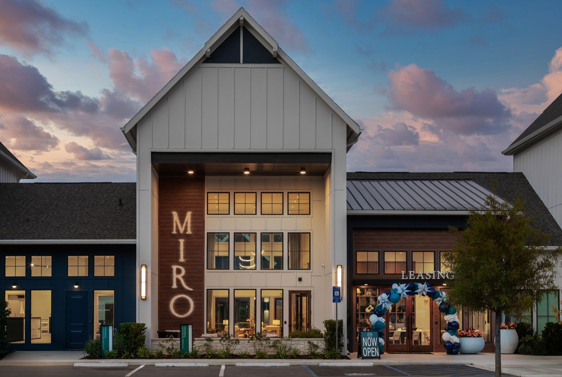 Exterior of the MIRO apartments building. White and brown facade, blue sky with dusk colors, event decorations.