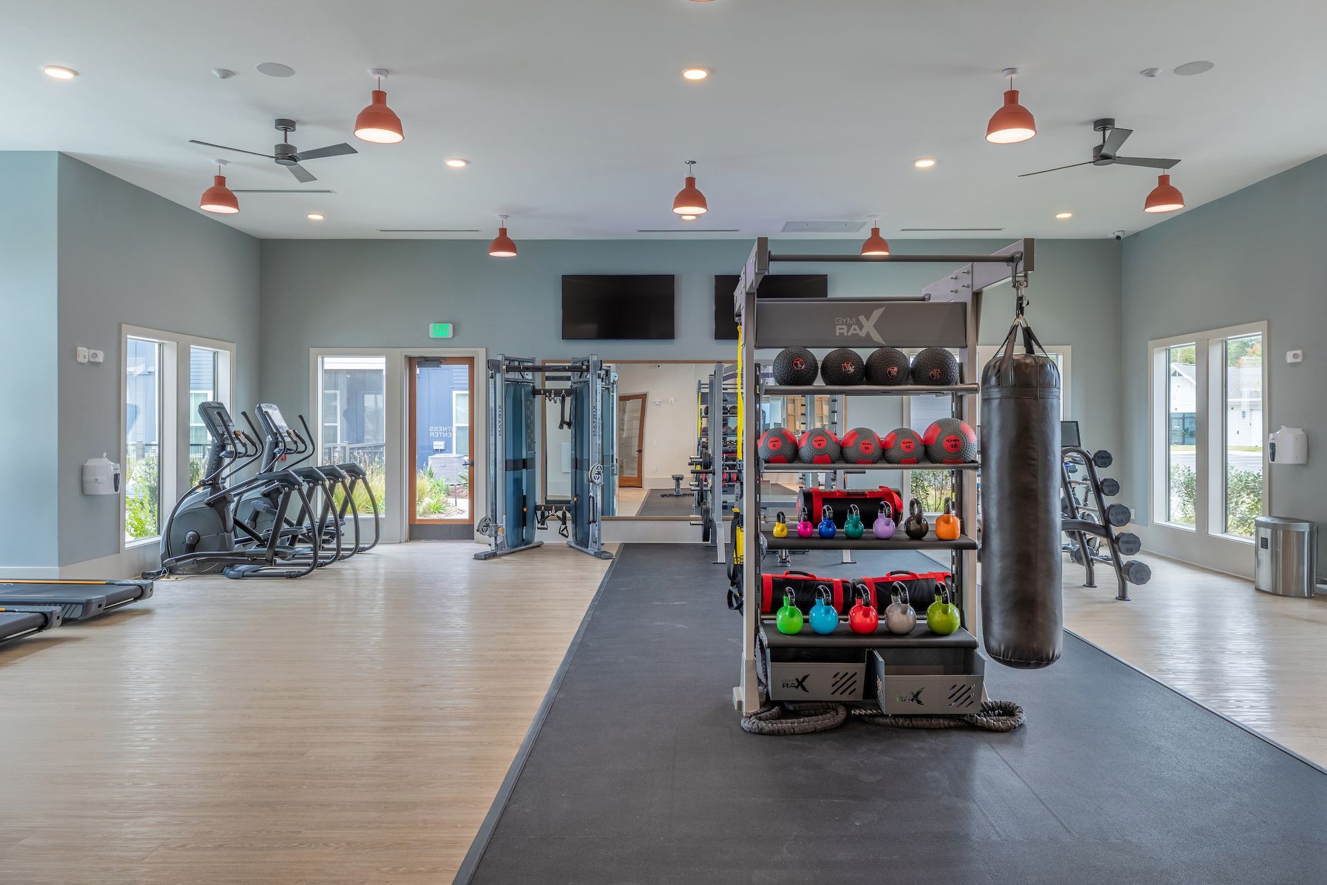 Gym interior with exercise equipment: treadmills, weights, and punching bag.